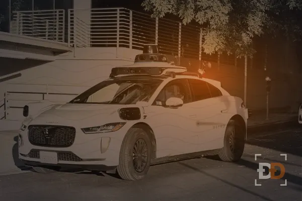 A white driverless SUV with a lidar dome and camera pods on its roof is parked on a city street.